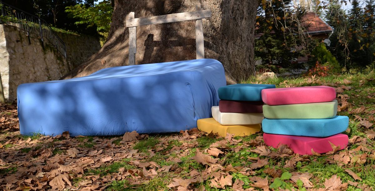 Blue fitted sheet on a mattress under a plane tree with stacks of folded sheets — Kayteks shoot in Babadağ