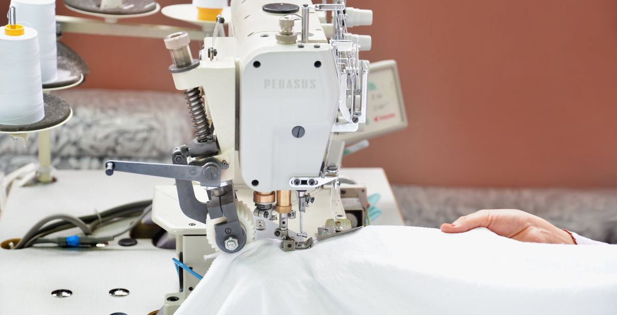 Sewing machine stitching white fabric in the Kayteks sewing room